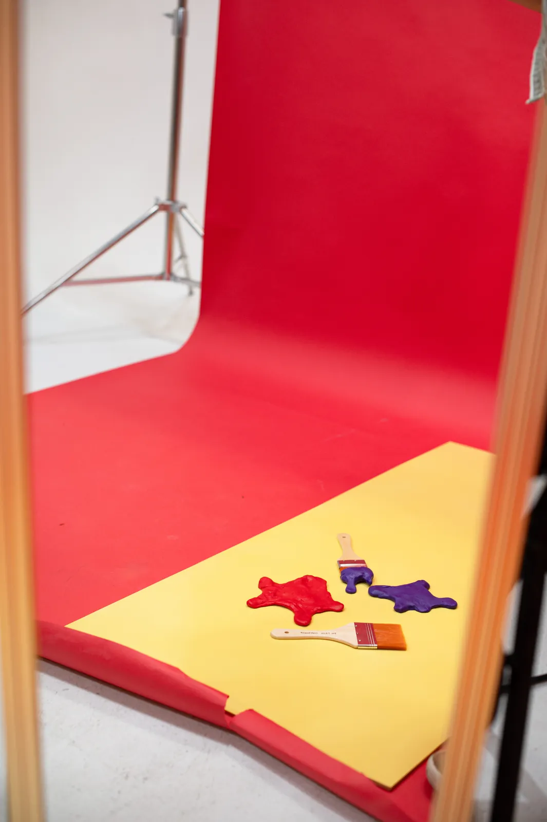 A second set on a yellow board, red and violet paint-splat shapes and brushes, framed between light stands.