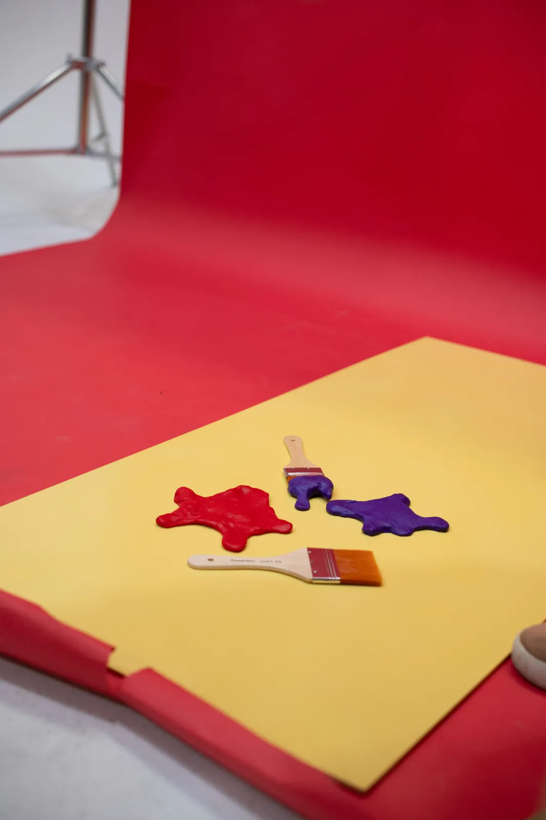 Closer on the yellow set: two paint splats and a pair of brushes laid out for the shot.