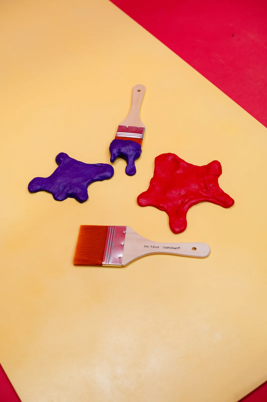A second overhead arrangement of the clay paint splats and brushes on yellow.
