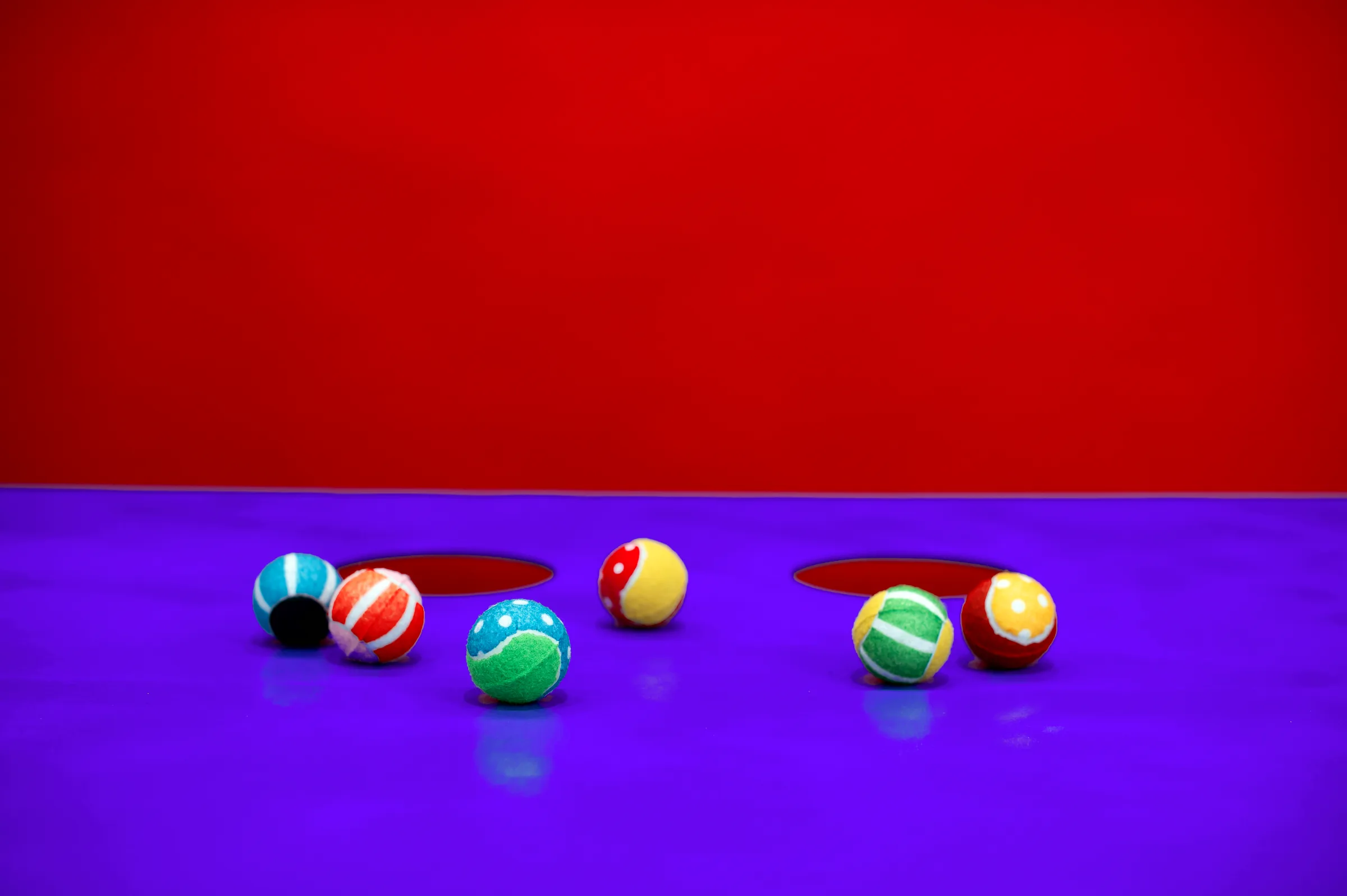 Colourful rubber balls scattered across the violet table.