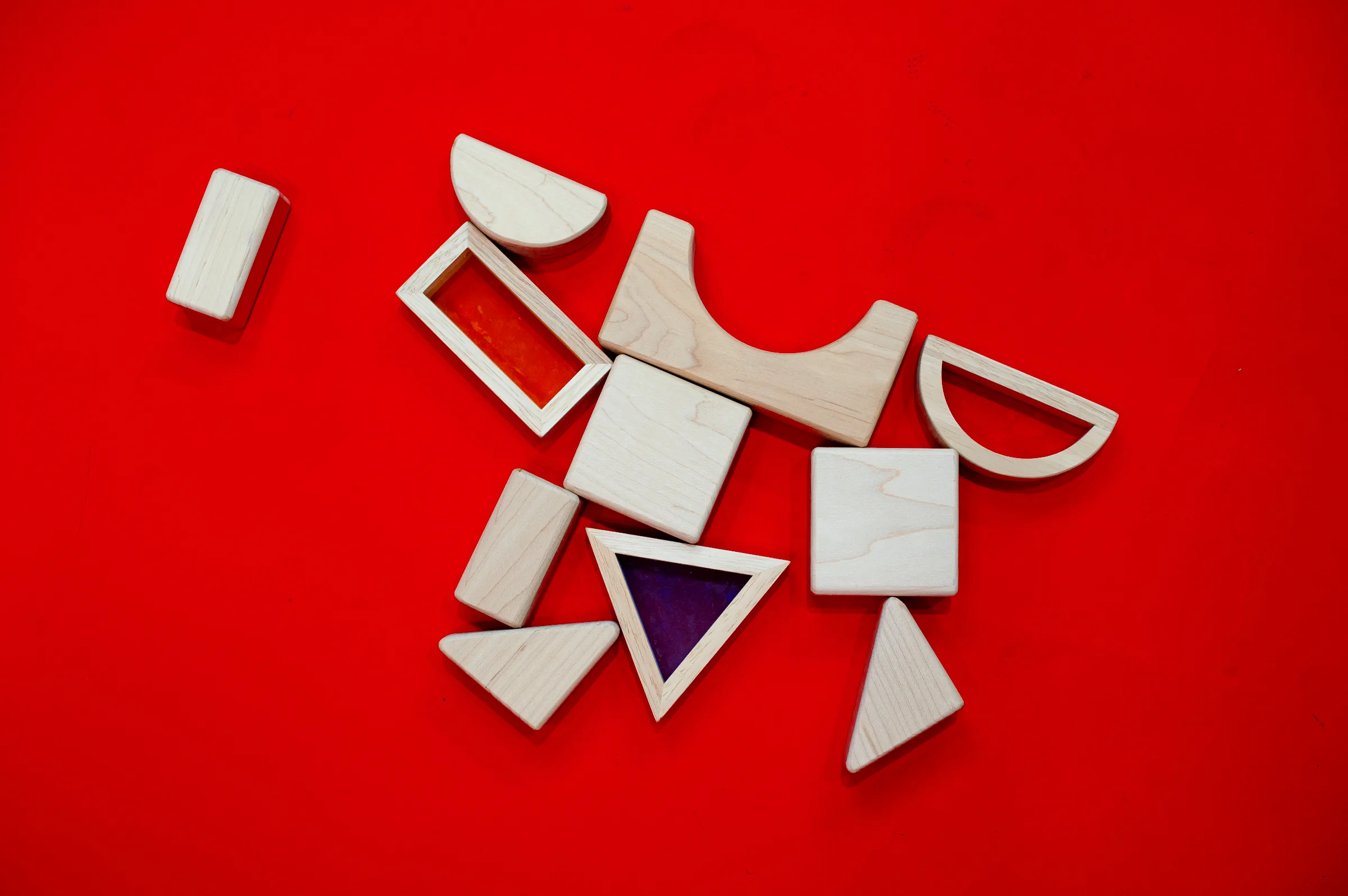 Wooden blocks with coloured windows scattered flat on red.