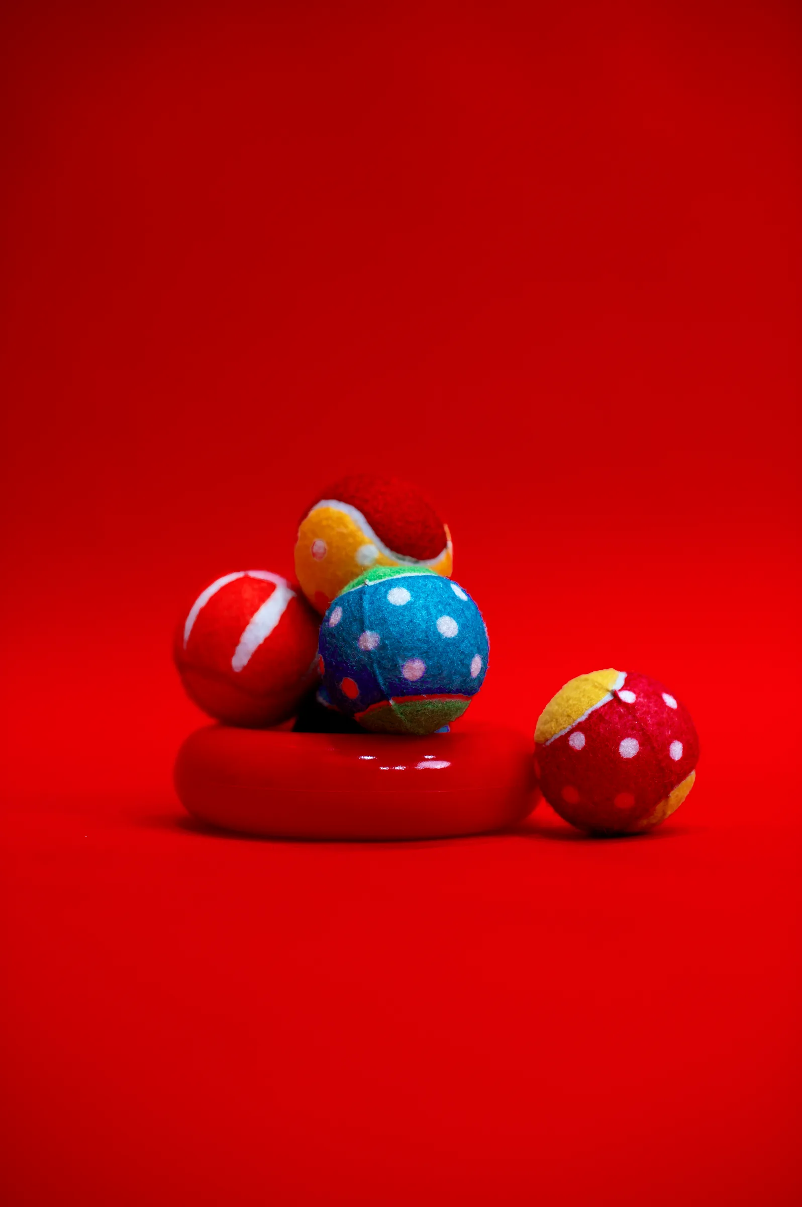 A small pile of patterned balls on a red ring, against red.